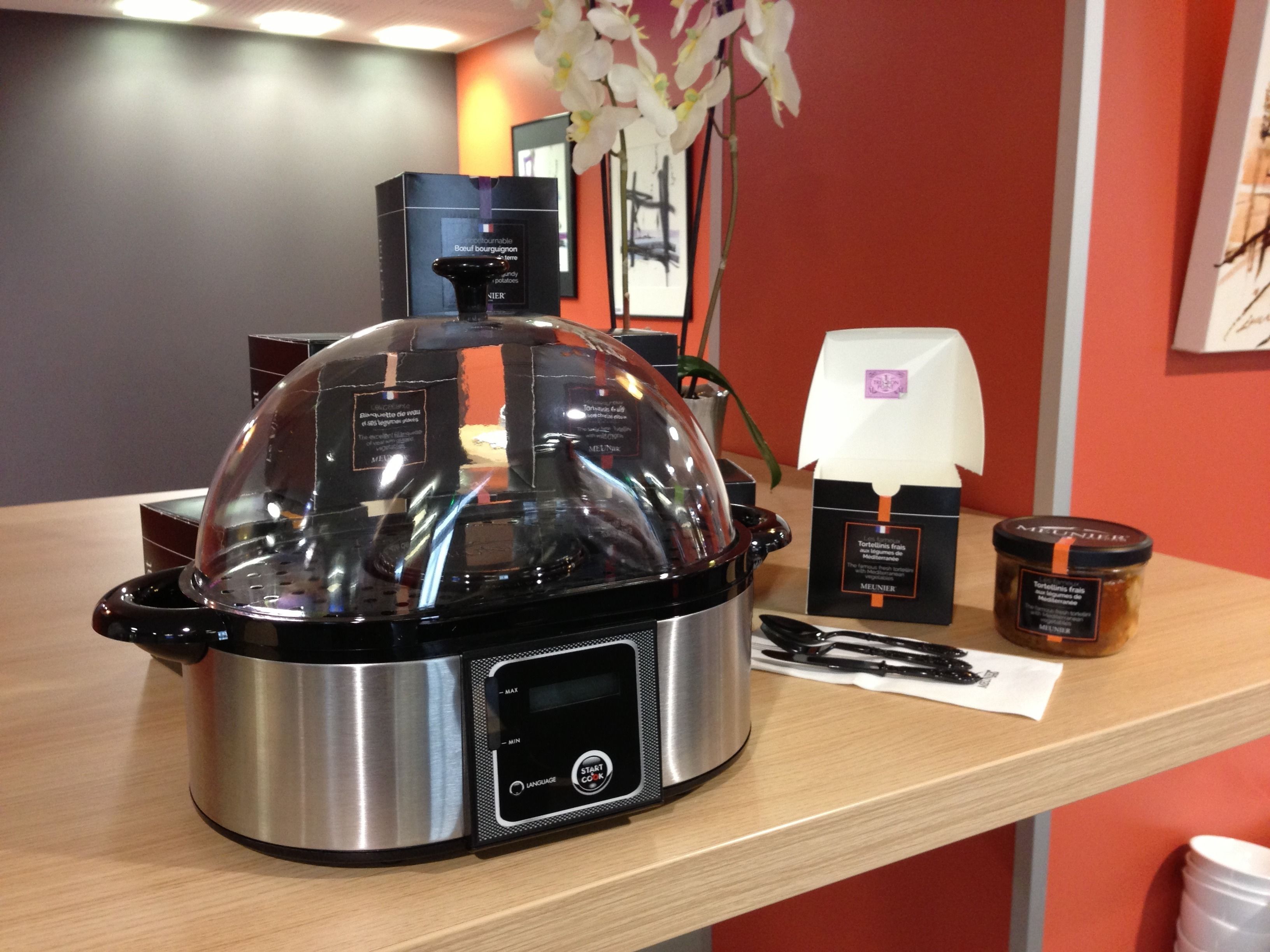 A kitchen with a modern electric pressure cooker on a wooden countertop.