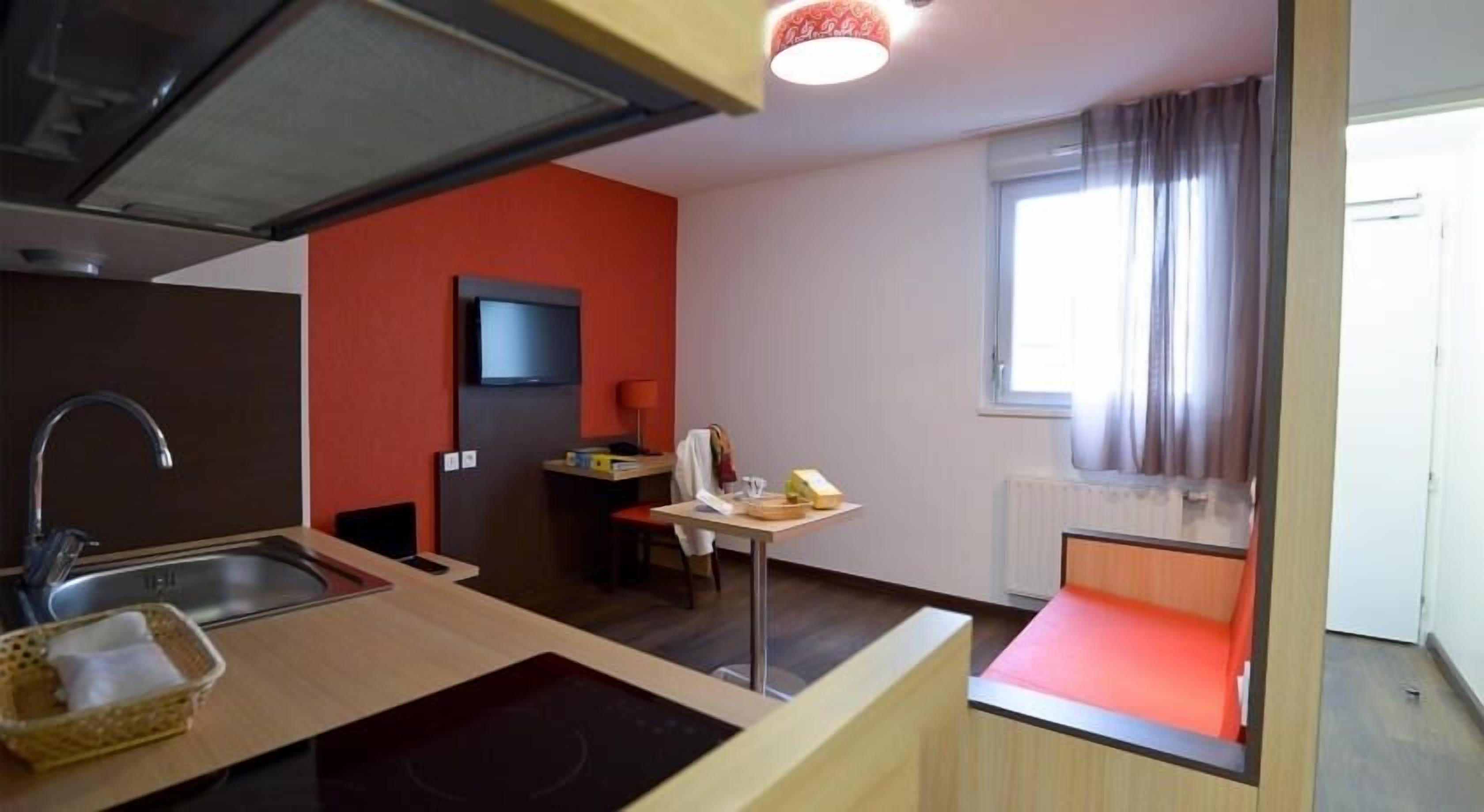 Una cocina compacta con fregadero, estufa y un pequeño comedor con mesa y silla.