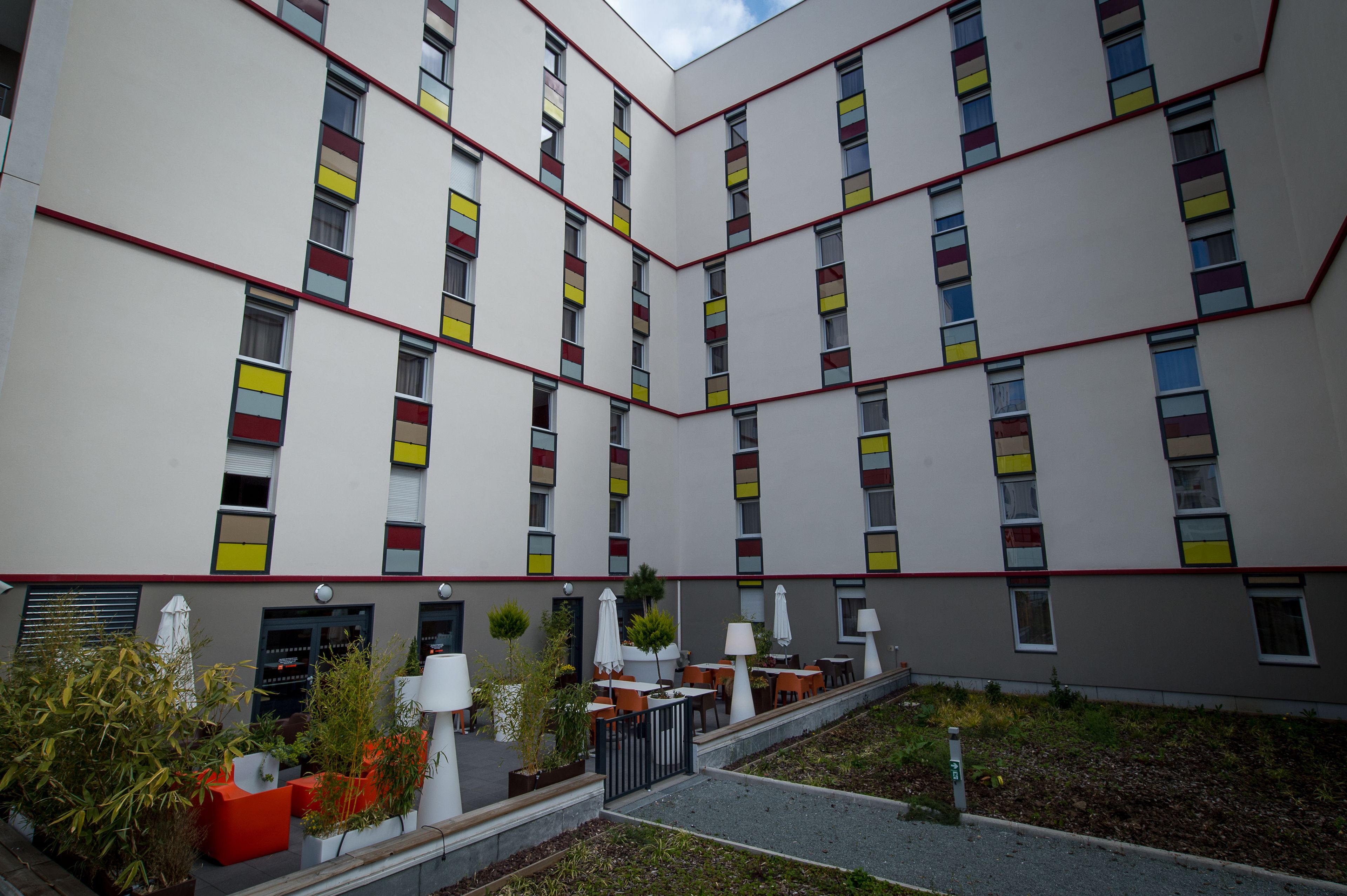 A modern building with a courtyard featuring outdoor seating and planters.