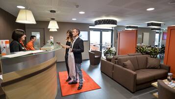A reception area with a curved wooden counter, a brown sofa, and a red carpet.