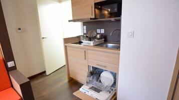 A compact kitchen with wooden cabinets, a stainless steel sink, and a dishwasher.