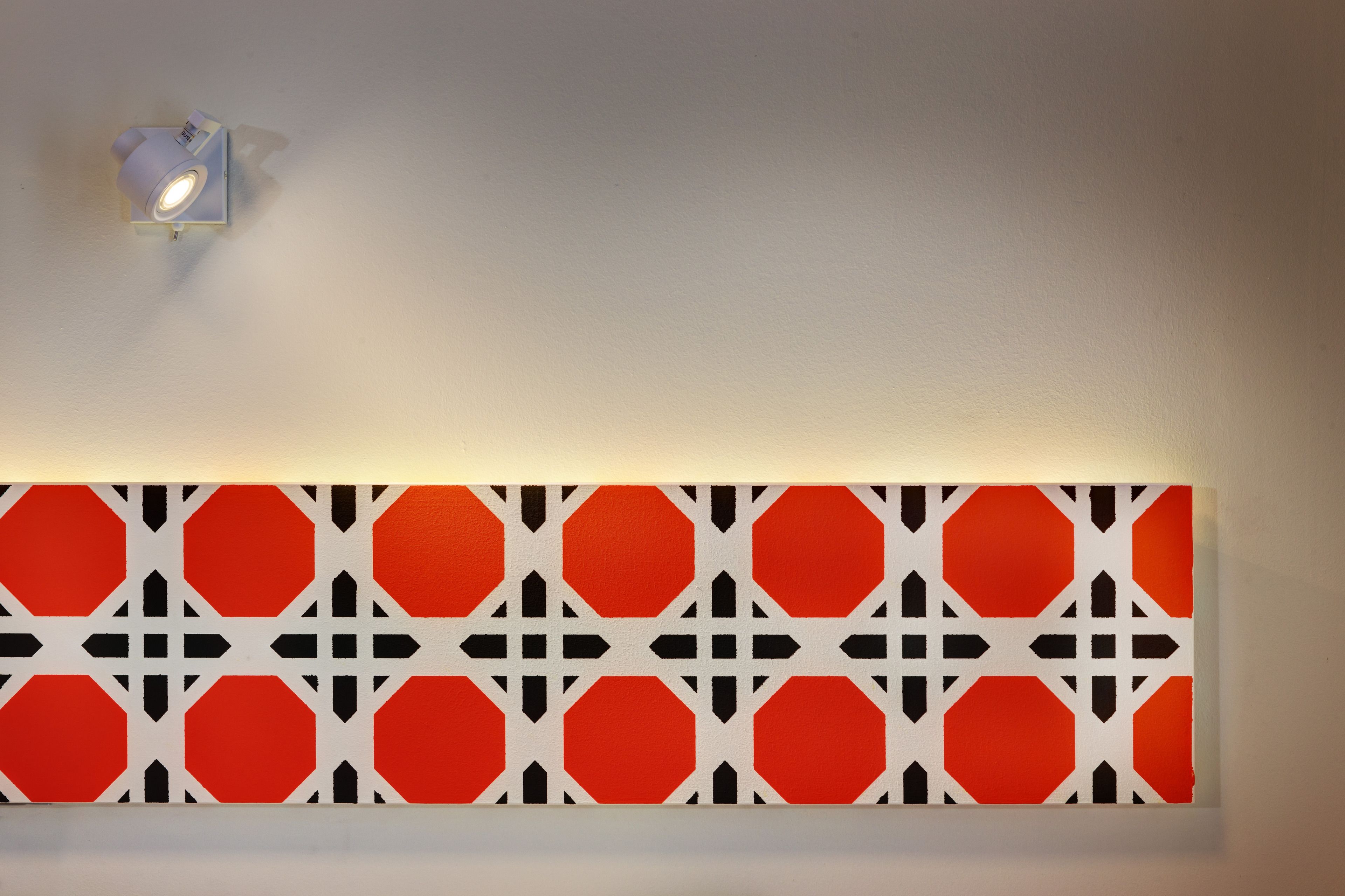Een muur met een geometrisch patroon van rode en zwarte vormen.
