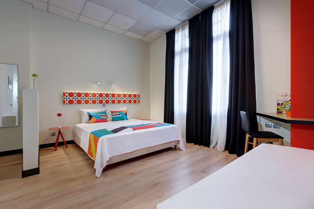 Moderni hotellihuone, jossa on sänky, työpöytä ja tuoli.