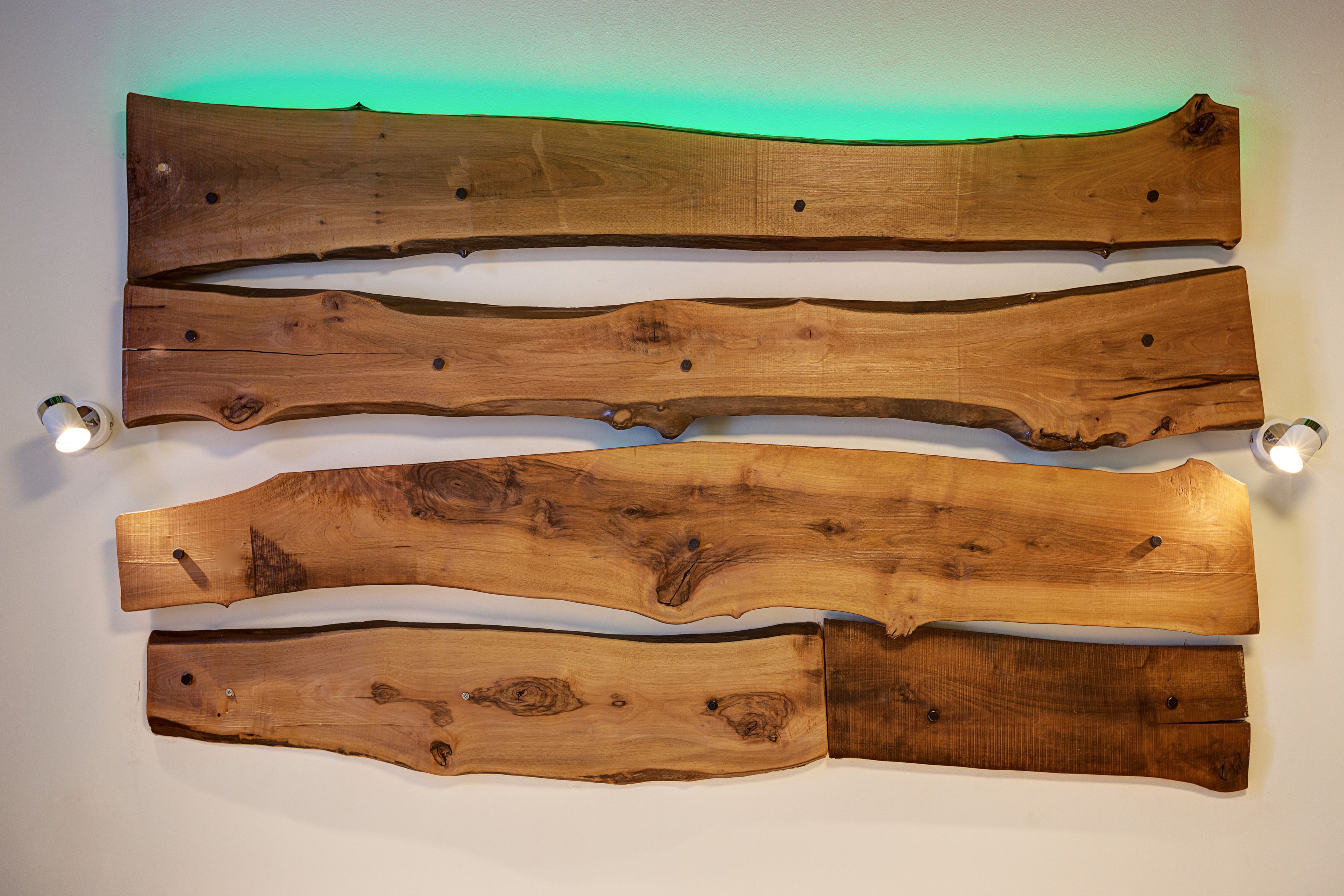 Vier houten planken horizontaal op een muur bevestigd.