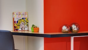 Un livre intitulé « POP ART » sur une étagère, une petite plante en pot et deux sphères réfléchissantes.