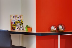 A book titled 'POP ART' on a shelf, a small potted plant, and two reflective spheres.