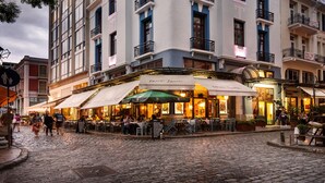 Un bâtiment historique doté de nombreux balcons et abritant un café au rez-de-chaussée.