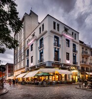 Ein historisches Gebäude mit mehreren Balkonen und einem Café im Erdgeschoss.