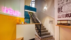 Un escalier avec une rampe en métal noir, un néon affichant le mot « BONJOUR » et une citation inspirante sur le mur.
