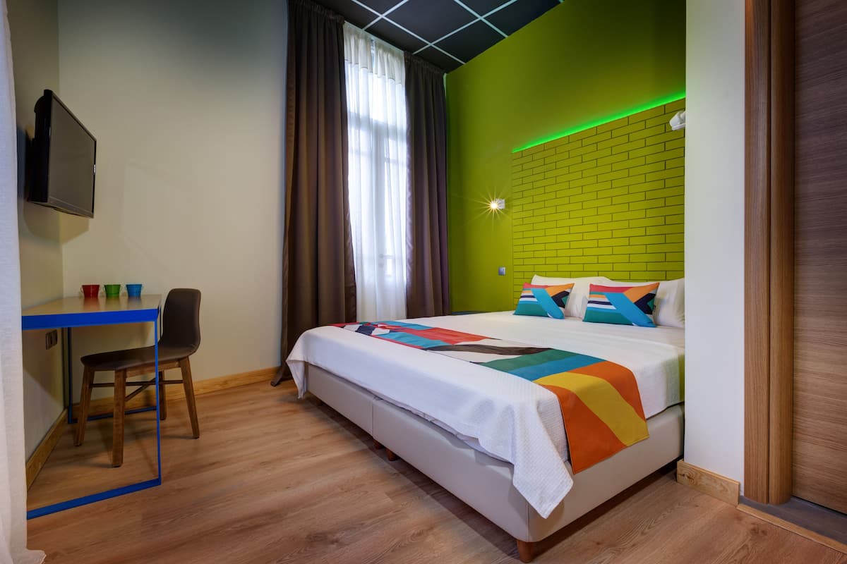 Hotellihuone, jossa on sänky, työpöytä ja tuoli.