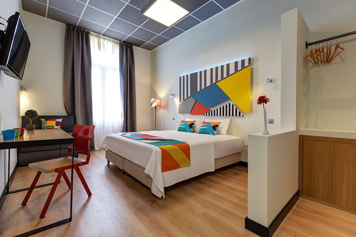 Moderni hotellihuone, jossa on sänky, työpöytä ja tuoli.