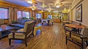 A cozy indoor space with a pool table, sofas, and a bar area.