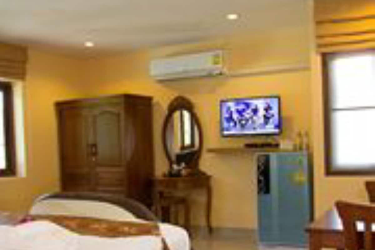 A hotel room with a bed, a desk, a chair, a television, and a wardrobe.