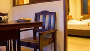 Una habitación de hotel con una cama, una silla de madera, una mesa y una ventana.