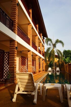 A hotel with a pool area, outdoor seating, and a palm tree. - Hathai House Resort (Koh Samui)