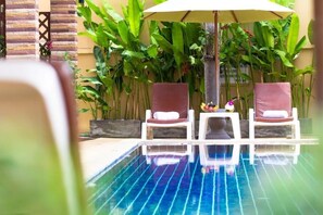 Un espace piscine comprenant deux chaises longues et un parasol.