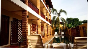 Un hotel con piscina, zona de estar al aire libre y palmeras.