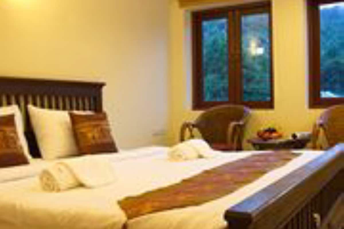 A bedroom with a wooden bed, pillows, a nightstand, and a window with a view.