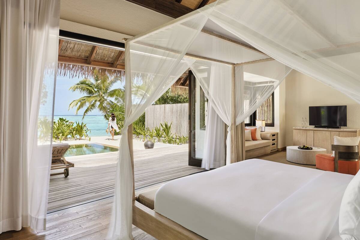 Un dormitorio con cama, televisor y vista al océano.