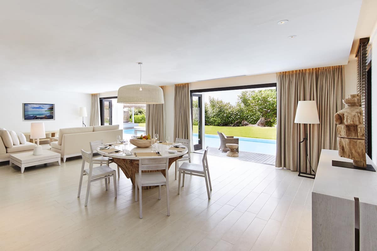 Amplia sala de estar con una mesa de comedor, sofás blancos y un ventanal con vistas al exterior.