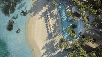 Relax by the pool surrounded by palm trees, with access to the pristine beach and clear waters.