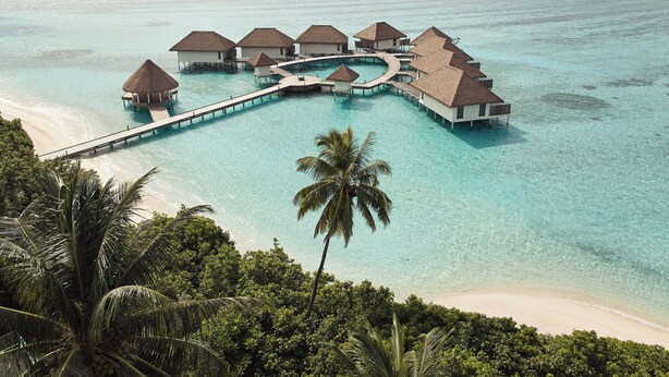 An overwater resort with multiple bungalow-style accommodations connected by walkways over clear turquoise waters. - COMO Maalifushi (Maalefushi)