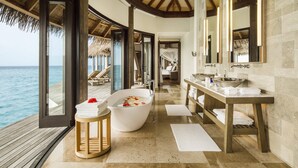 A luxurious bathroom with a large bathtub, a wooden vanity, and a view of the ocean. - COMO Maalifushi (Maalefushi)