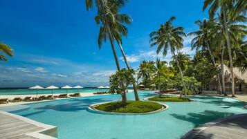 Una piscina al aire libre, sombrillas, sillones reclinables de piscina
