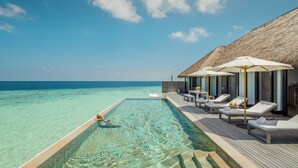 A clear poolside area with lounge chairs and umbrellas, overlooking a turquoise sea. - COMO Maalifushi (Maalefushi)