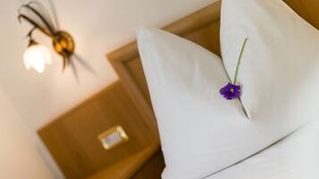 A white pillow with a purple flower on a bed in a hotel room.
