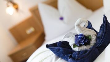 Un lit bien fait, avec une serviette bleue et un coussin décoratif orné d’une fleur bleue.