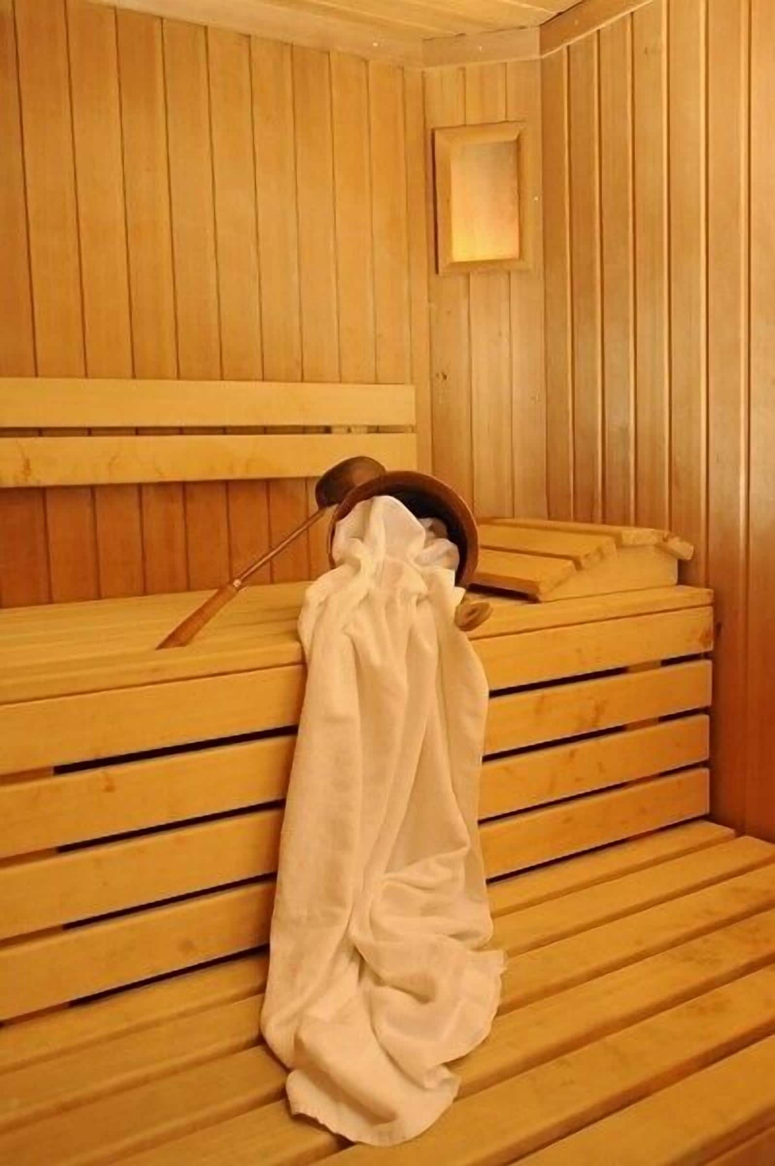 Un sauna avec des bancs en bois et un banc muni d’une serviette.