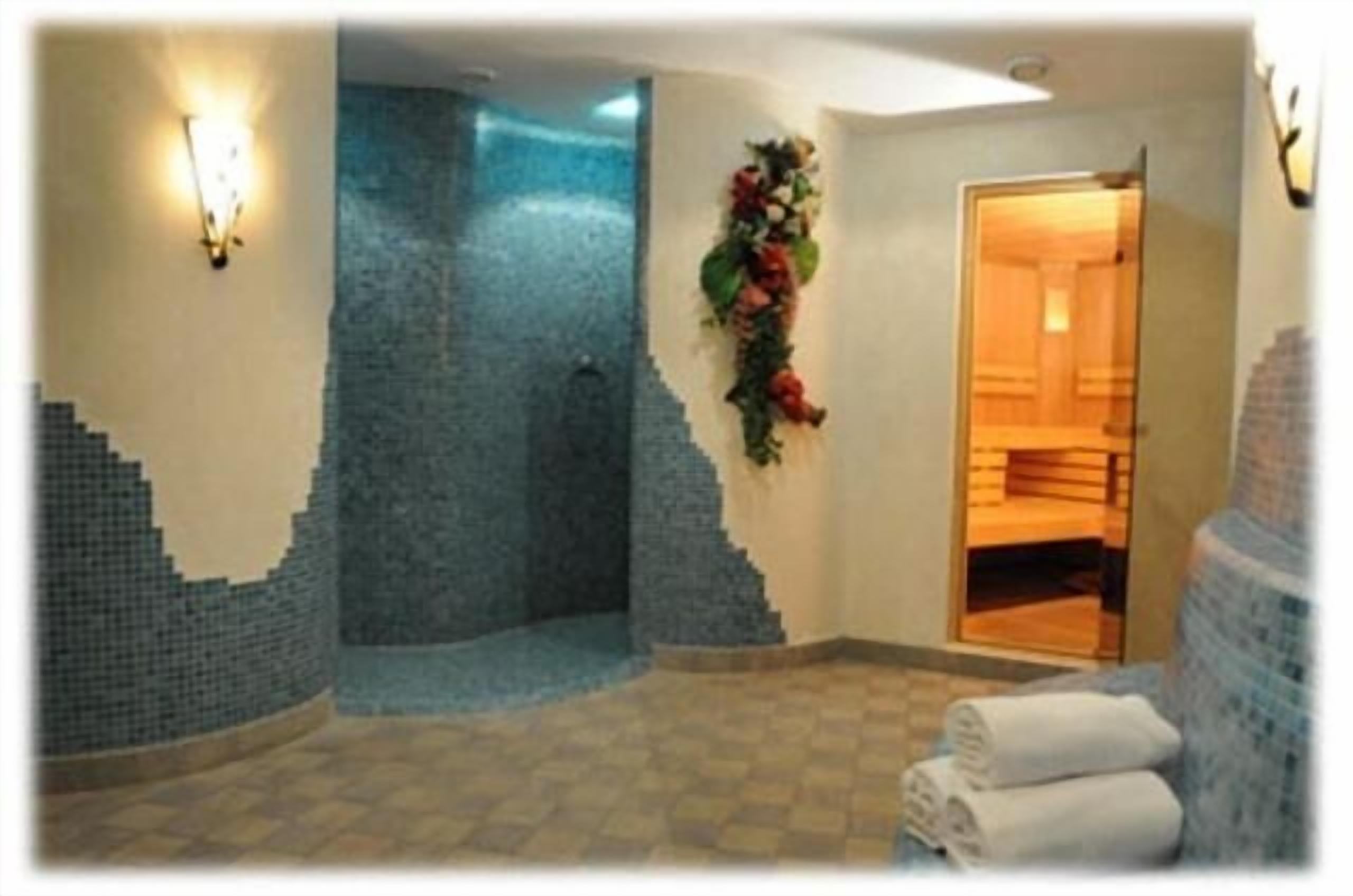 Une salle de bain avec un mur décoré de mosaïques, un espace douche et une porte donnant sur une autre pièce.