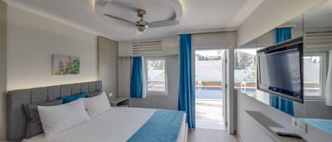 A modern hotel room with a bed, a ceiling fan, a TV, and a view of the outdoors.