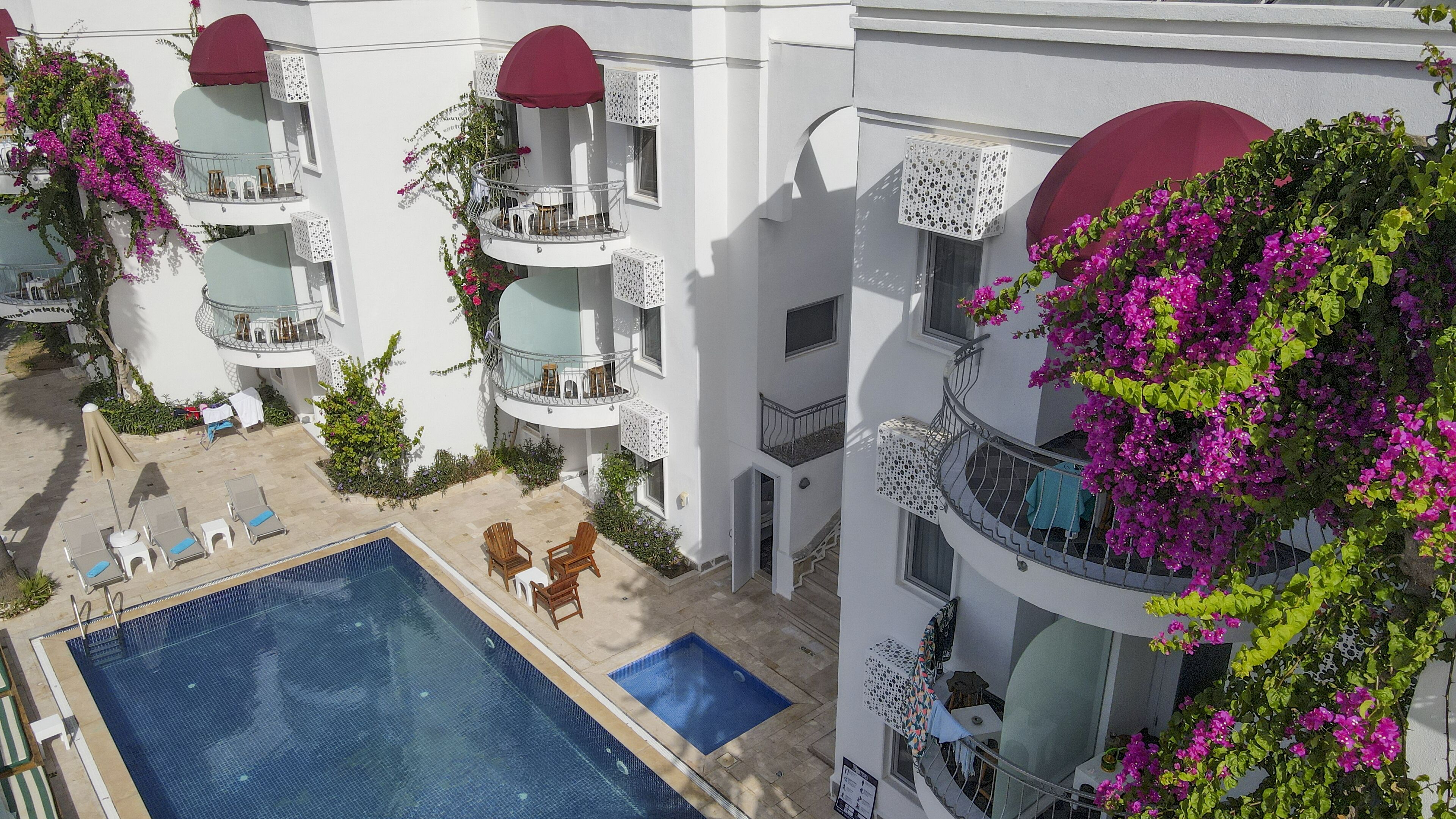 Un immeuble à plusieurs étages doté de balcons, d’une piscine et d’une végétation luxuriante.