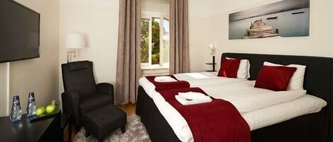 Habitación de hotel con cama, escritorio, silla, televisión y un cuadro en la pared.