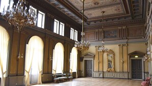 A spacious hall with high ceilings, ornate chandeliers, and large windows with curtains. - Statt Kristinehamn (Kristinehamn)