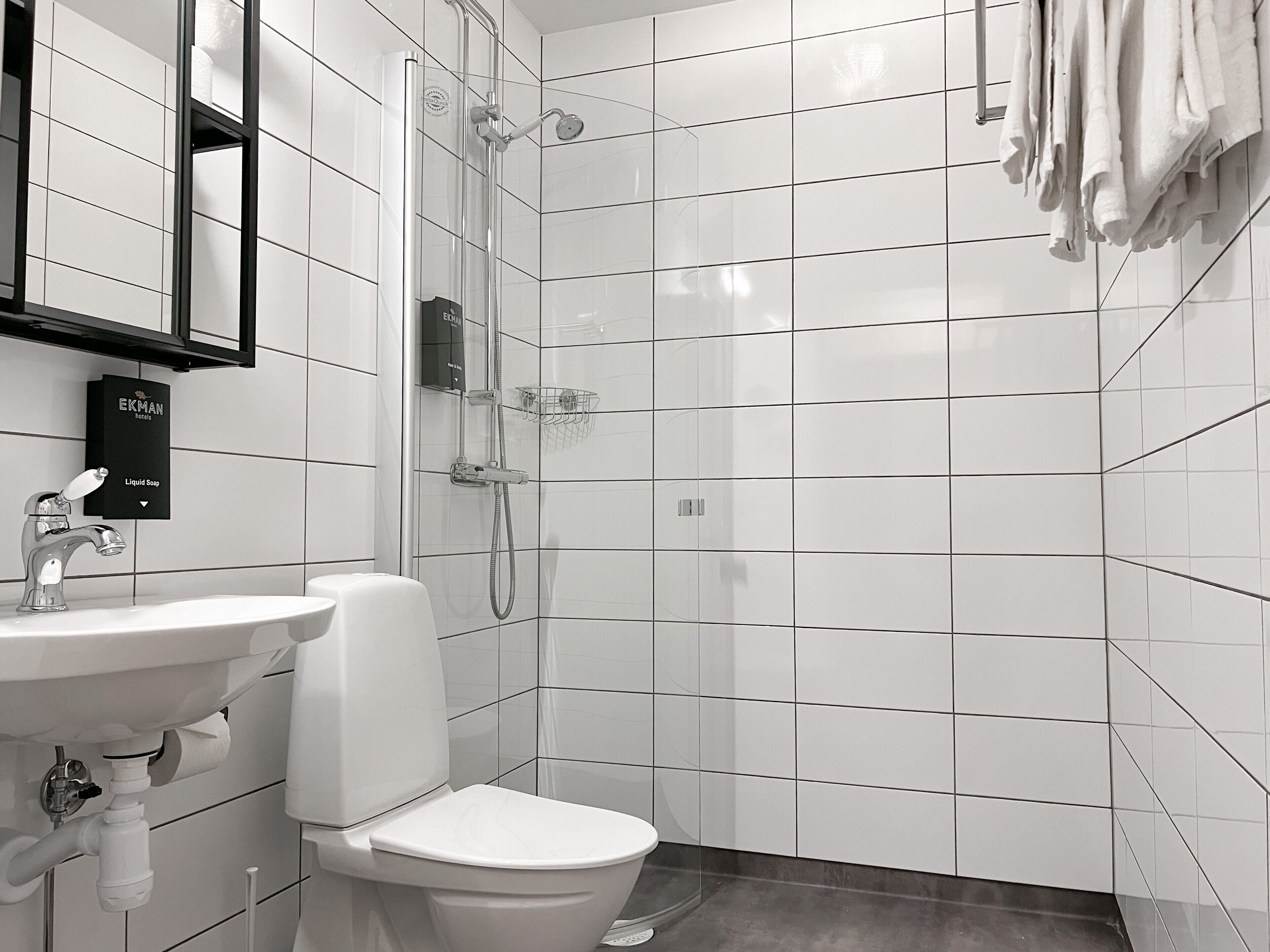 A modern bathroom with a white sink, toilet, and shower.