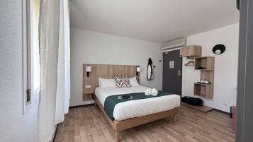 Una camera d'albergo con un letto in legno, un comodino, un armadio e una mensola a parete.