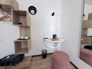 A modern room with a wooden wardrobe, a round mirror, a white sink, and a pink ottoman. - Atena Bordeaux Sud Est Créon - Vélo Friendly (Créon)