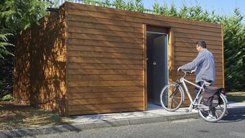 Een klein houten gebouw met een deur en een fiets ervoor geparkeerd.