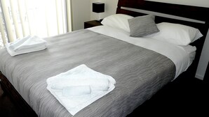 A neatly made bed with a grey and white striped bedspread, two pillows, and a folded white towel on the side. - Monterey Moranbah (Moranbah)