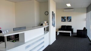 A reception area with a white desk, a clock, and two abstract paintings on the wall. - Monterey Moranbah (Moranbah)