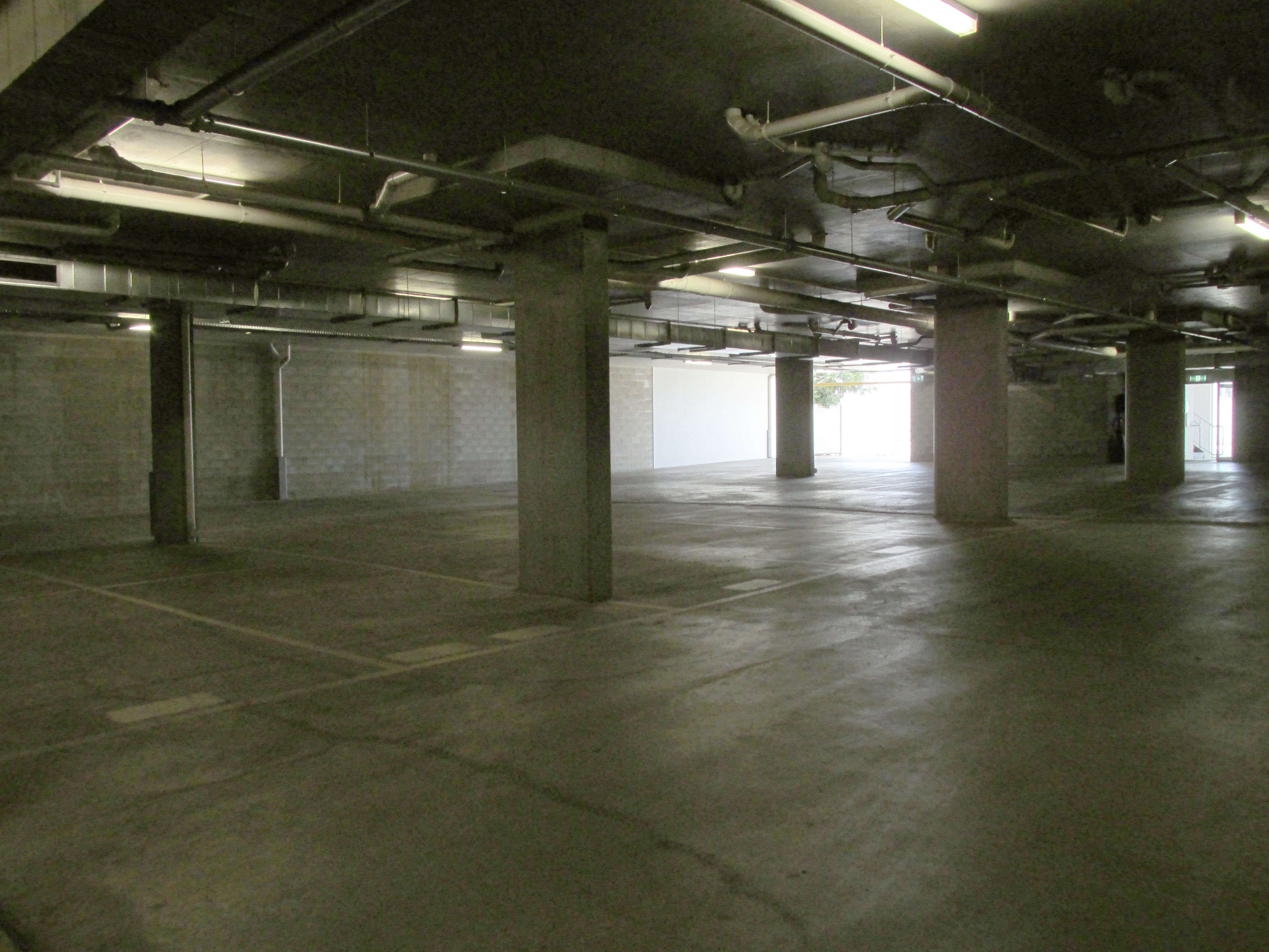Garagem subterrânea com pilares de concreto e iluminação fluorescente.