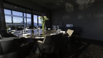 A dining area with a table set for six, large windows, and a view of the mountains.
