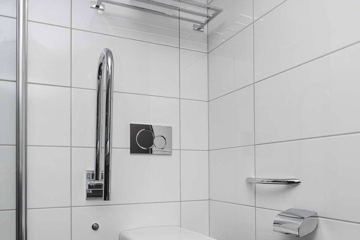 Un baño moderno con inodoro, secamanos, toallero y dispensador de papel higiénico.