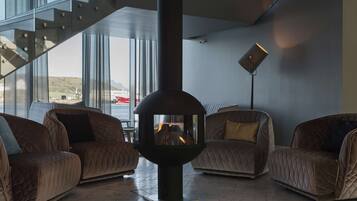 A modern interior with a fireplace, leather sofas, and a staircase leading to an outdoor area.