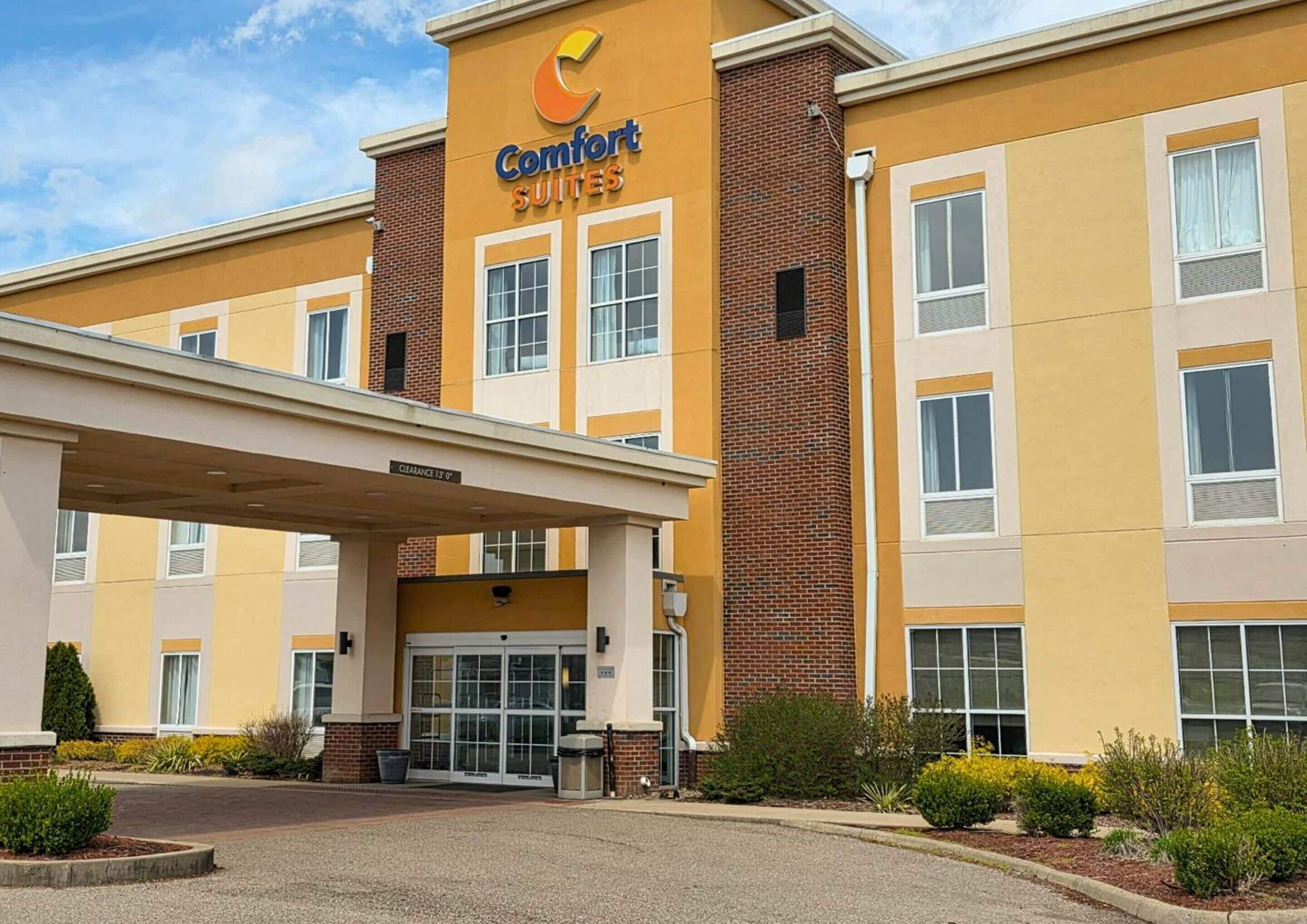 Un hotel Comfort Suites con fachada de ladrillo, ventanas grandes y entrada cubierta.