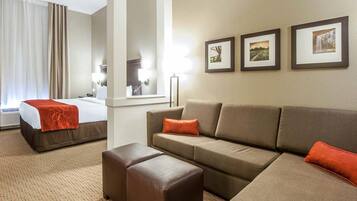 Quarto de hotel com uma cama, um sofá, um banquinho e três quadros na parede.