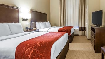 A hotel room with two beds, a TV, a desk, and a chair.